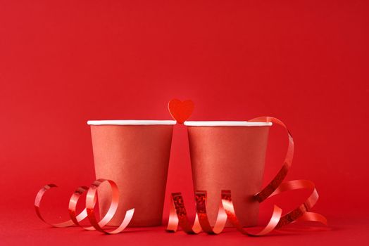 Two red paper coffee cup and heart on red background. Romantic and valentines day concept