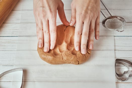 Woman kneads dough with hands in kitchen