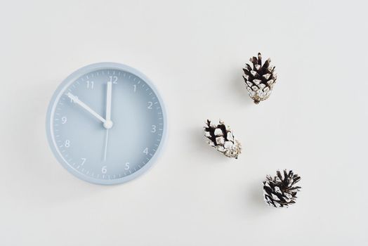 Alarm clock with pine cones on white background, top view. Minimal creativity flat lay style