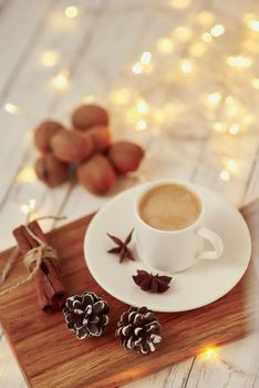 Cozy autumn or winter concept. Cup of coffee with garland lights and decoration/