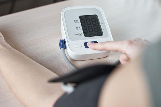 Woman measuring blood pressure with electric digital tonometer. Healthcare and medicine concept