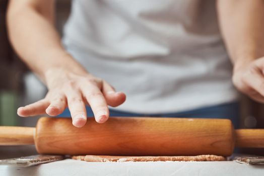 Female hands rolling dough on table. closeup. Woman making dough for baking in the kitchen