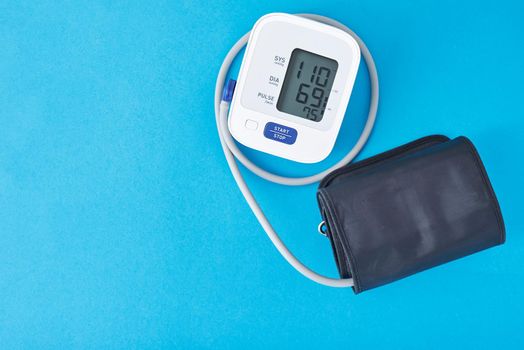 Digital blood pressure monitor on blue background, closeup. Helathcare and medical concept