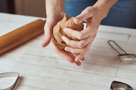 Woman kneads dough with hands in kitchen