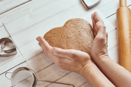 Woman kneads dough with hands in kitchen