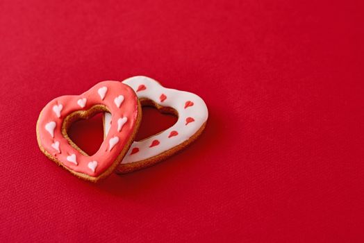 Two decorated with icing and glazed heart shape cookies on red background with copy space. Valentines Day food concept