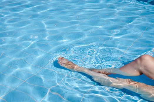 Female legs in water pool. Summer holiday