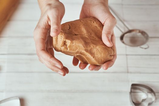 Woman kneads dough with hands in kitchen