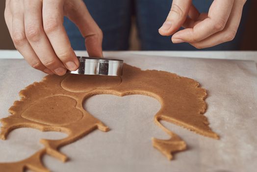 Making gingerbread cookies in shape of a heart for Valentines Day. Woman hand use cookie cutter. Holiday food concept