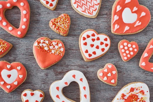 Background of decorated with icing and glazed heart shape cookies on gray background, flat lay. Valentines Day food concept