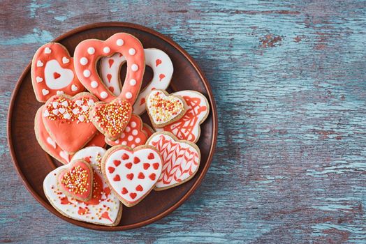 Decorated heart shape cookies in plate on gray background. Valentines Day food concept