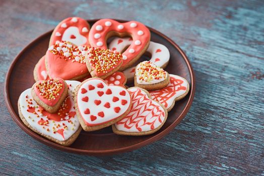 Decorated heart shape cookies in plate on gray background. Valentines Day food concept