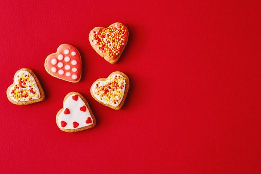 Decorated with icing and glazed heart shape cookies on red background with copy space. Valentines Day food concept