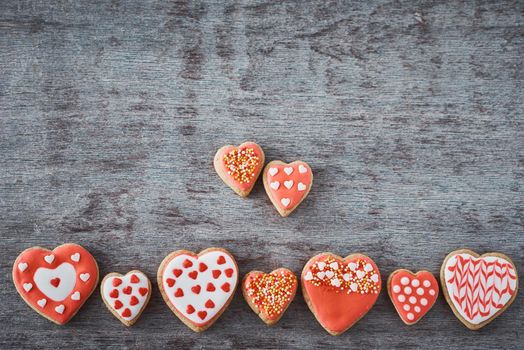 Background of decorated with icing and glazed heart shape cookies on gray background, flat lay. Valentines Day food concept