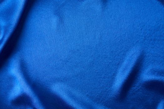 Blue silk background with folds. Abstract texture of rippled satin surface