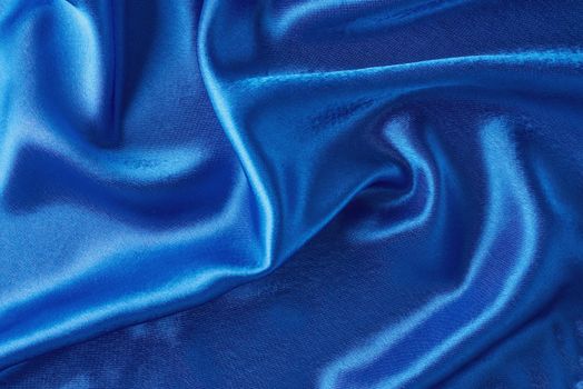 Blue silk background with folds. Abstract texture of rippled satin surface