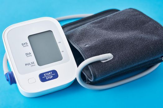 Digital blood pressure monitor on blue background, closeup. Helathcare and medical concept