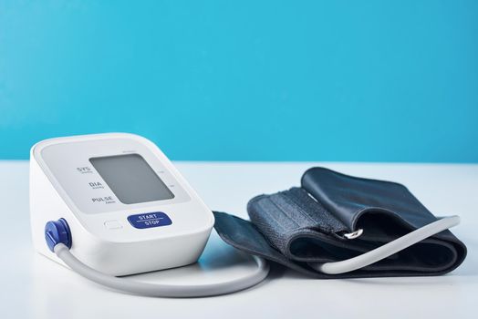 Digital blood pressure monitor on blue background, closeup. Helathcare and medical concept