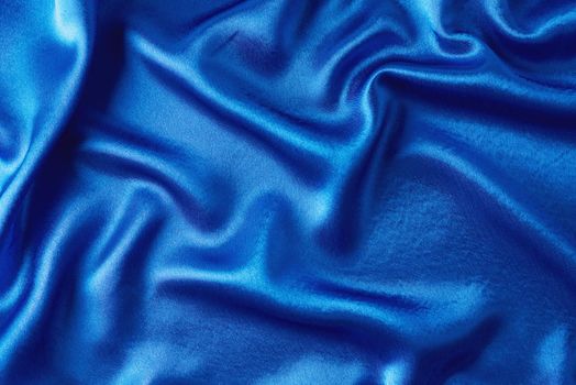 Blue silk background with folds. Abstract texture of rippled satin surface