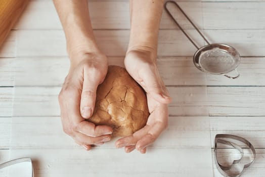 Woman kneads dough with hands in kitchen