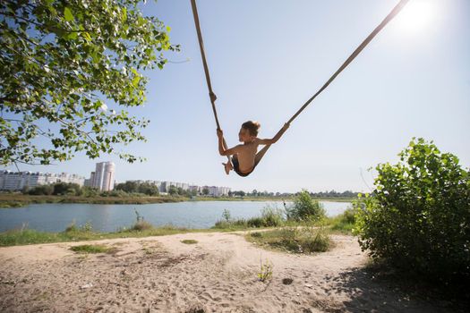A child is riding on a rope village swing