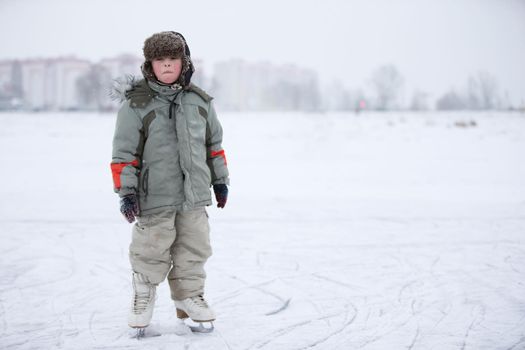 A child is a boy on skates on a snowy lake. Learn to ride