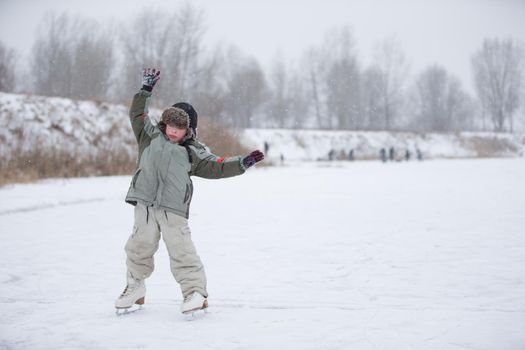 The kid learn to skate. The boy on the lake in winter snowy day on skates. Skating on the lake