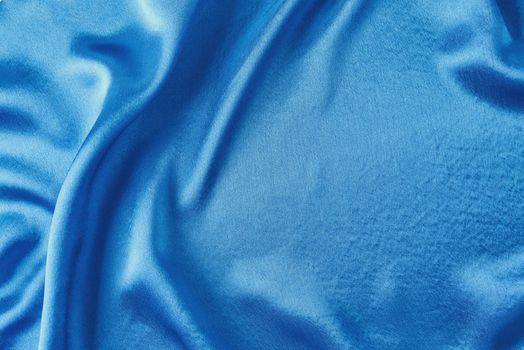 Blue silk background with folds. Abstract texture of rippled satin surface