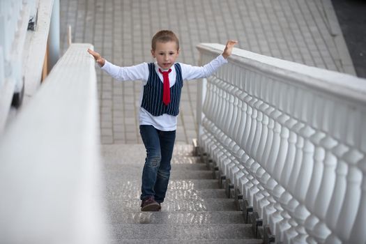 A child in a tie climbs up the stairs