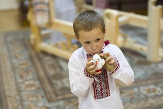 The Belarusian boy. Belarusian boy in national clothes with a toy clay cockerel. Children's ethnic ancient Slavic toys.A boy with a toy whistle