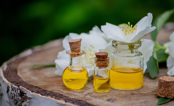 Essential oil and jasmine flowers on a wooden background. Cosmetic procedures. Selective focus