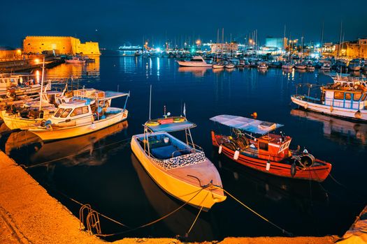 Venetian Fort castle in Heraklion and moored Greek fishing boats in port, Crete Island, Greece in the night