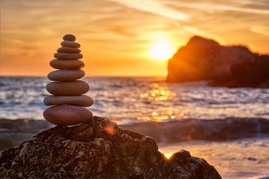 Concept of balance and harmony. Cairn stack of stones pebbles cairn on the beach coast of the sea in the nature on sunset. Meditative art of stone stacking