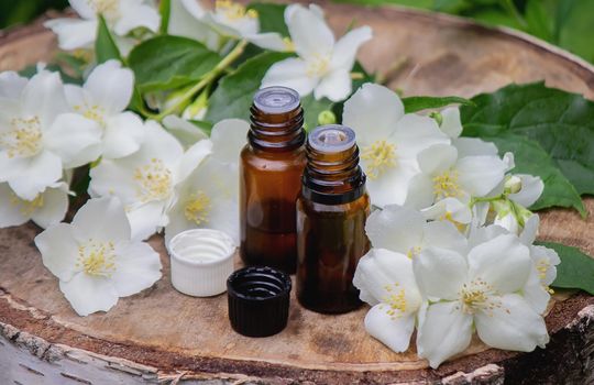 Essential oil and jasmine flowers on a wooden background. Cosmetic procedures. Selective focus