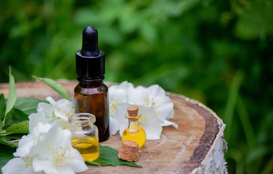 Essential oil and jasmine flowers on a wooden background. Cosmetic procedures. Selective focus