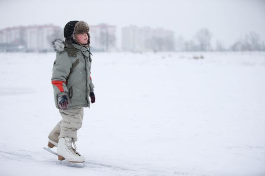 Ice skating boy on the lake.The boy is skating on the lake. Little baby in huge skates