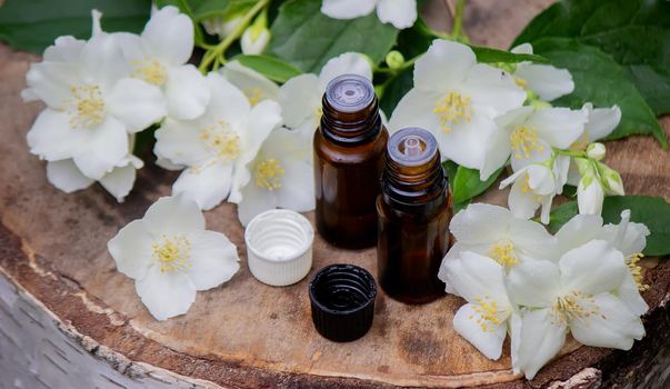 Essential oil and jasmine flowers on a wooden background. Cosmetic procedures. Selective focus