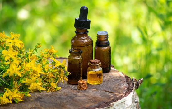 St. John's wort flower oil in a glass bottle. on a wooden background. Selective focus