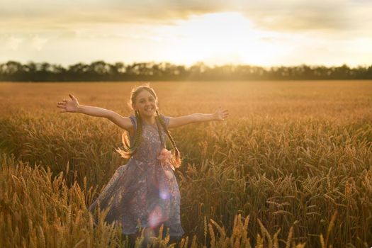 Girl running in wheat field at a sunset