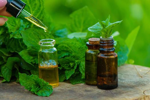 Amber bottle with essential oil Peppermint with fresh mint leaves, herbal scent in a dark glass jar. Aromatherapy concept. Selective focus