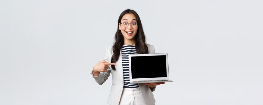 Business, finance and employment, female successful entrepreneurs concept. Enthusiastic office manager showing her presentation on laptop, pointing at screen and smiling amused.