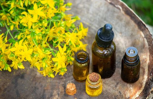 St. John's wort flower oil in a glass bottle. on a wooden background. Selective focus