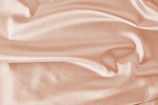 Light pink silk background with folds. Abstract texture of rippled satin surface