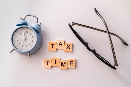 Close-up of alarm clock next to tax time concept on chalkboard.