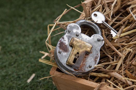 Old vintage iron padlock and key on straw background in wooden box. Copy spce, Selective focus.