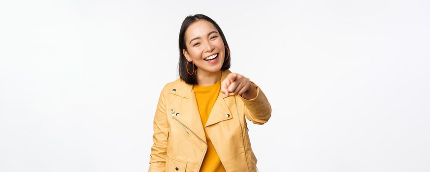 Congratulations, its you. Happy beautiful asian woman laughing, pointing finger at camera, choosing, inviting people, recruiting, standing over white background.