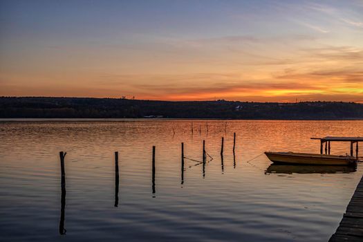 Moored wooden boat at the wooden pier after sunset 