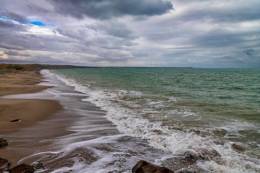 Beauty cloudy seascape with waves flowing at the empty beach.