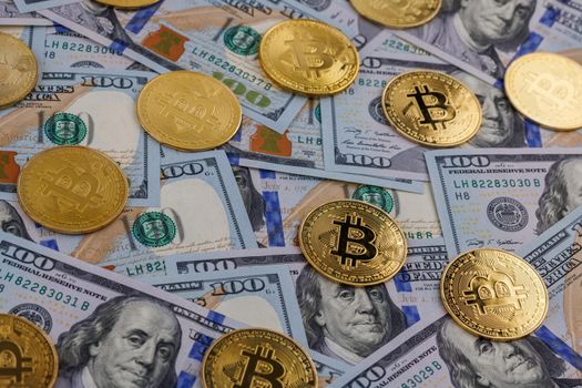 yellow bitcoin coins scattered over US dollar paper banknotes, cryptocurrency and fiat money exchange concept, closeup with selective focus