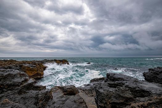 Stunning seascape with scenic clouds over the sea with rocky shore
